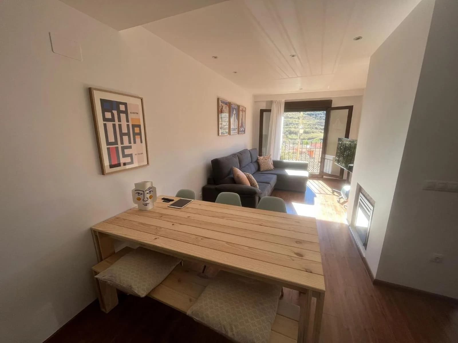 Salón-comedor del apartamento con mesa de madera y sofá, con vistas al valle de Camarena de la Sierra