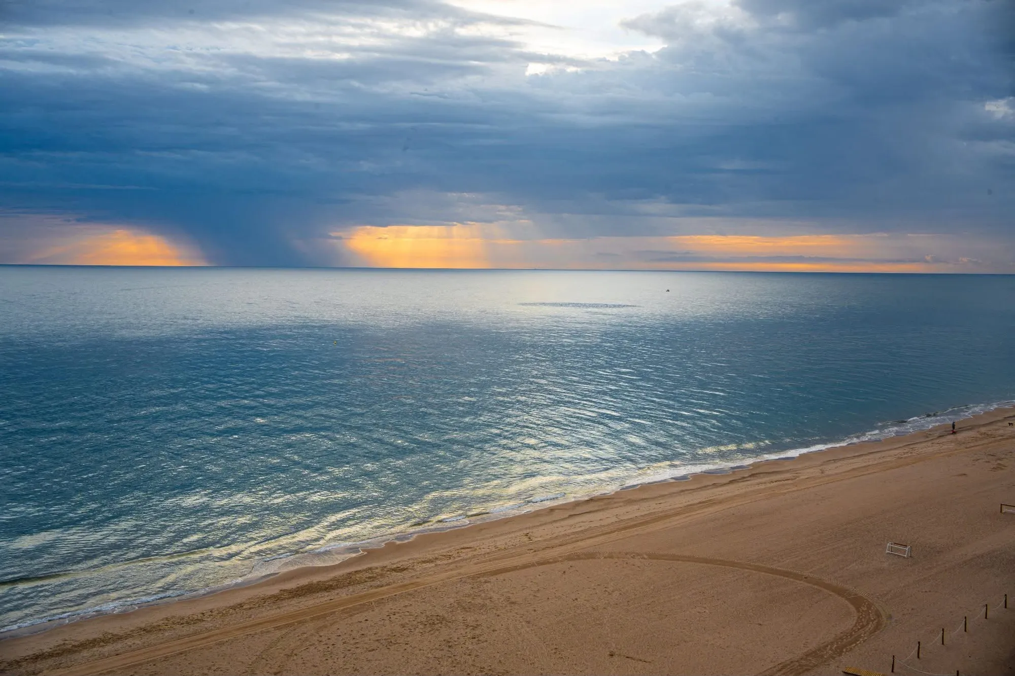 Rayos de sol entre nubes de tormenta sobre el Mediterráneo y la playa de la Llastra, vistos desde el ventanal del apartamento